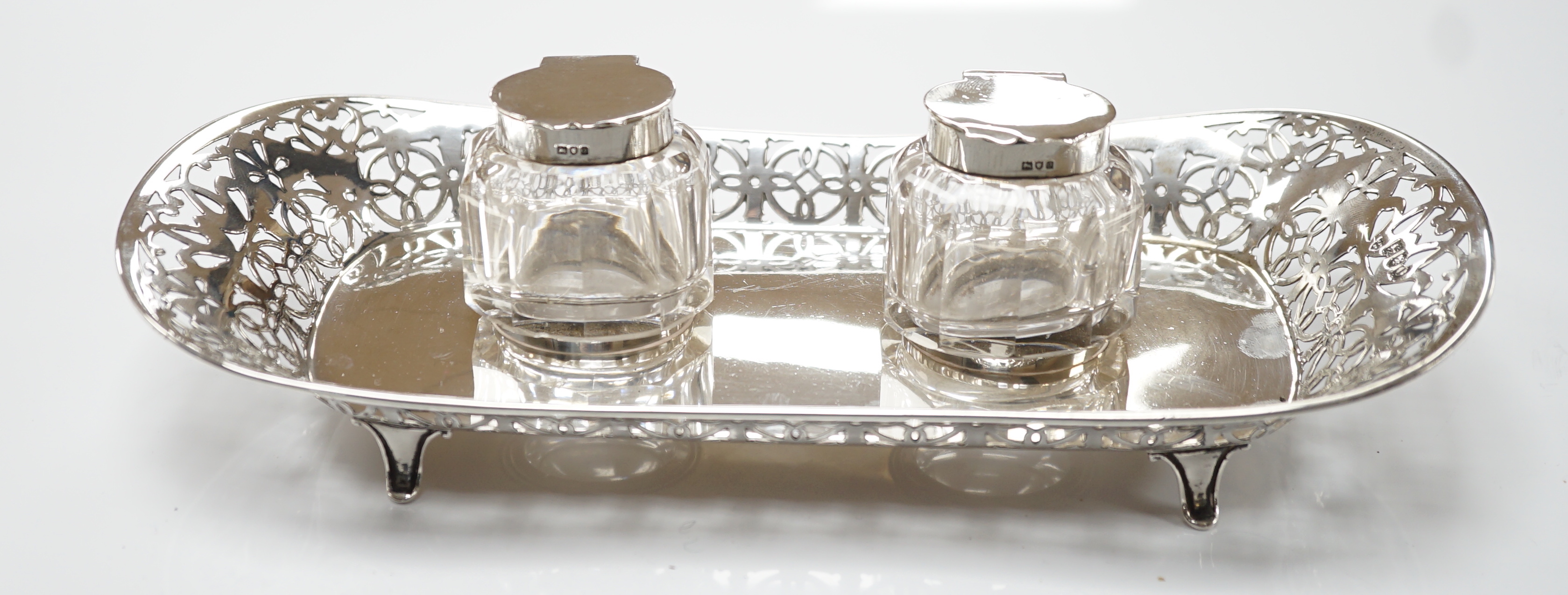 An Edwardian pierced silver inkstand, with two mounted glass wells, on four feet, Haseler Brothers, London, 1909, 26.2cm, 6.5oz.